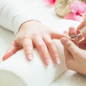 profesional de estética realizando un servicio de manicura a una mujer en un taller de manicura